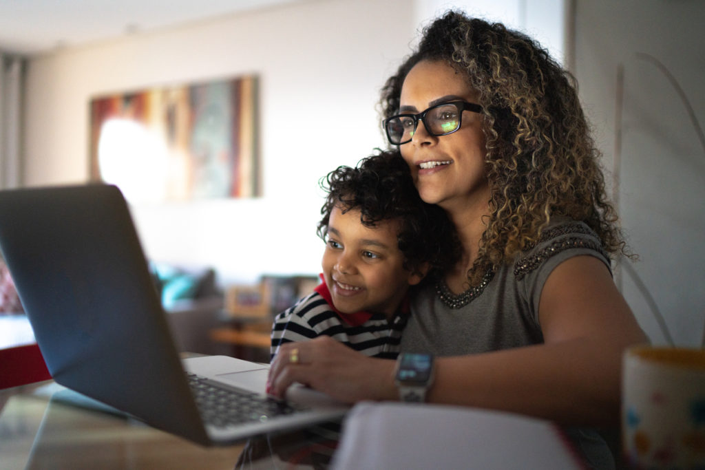 Mature woman working at home, carrying young son