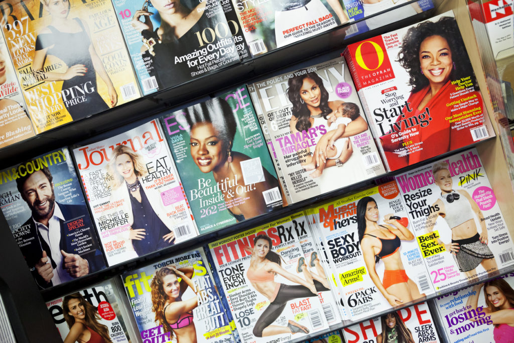 New York City, USA - October 1, 2013: Stack of popular magazines on the outside of the street side newsstand on Broadway Upper West. The Oprah Magazine, Ebony, Essence, Women Health and fitness magazines can be seen.