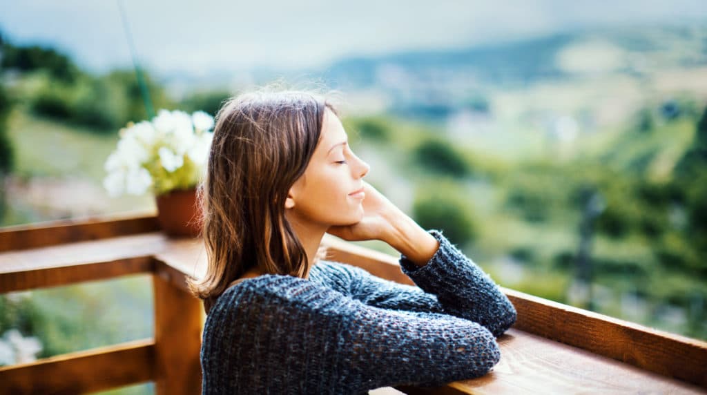 Young woman enjoying a fresh air on the mountain during summer morning.